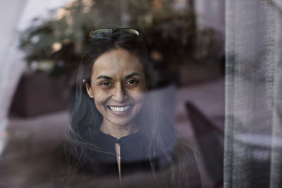 Portrait of smiling businesswoman by glass window in office