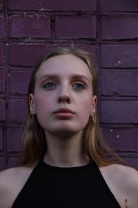 Portrait of young woman against wall