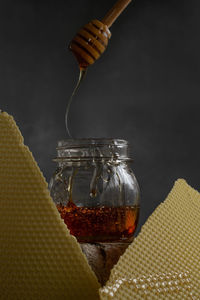 Jar with raw honey and bee comb on dark background, healthy nutrition concept