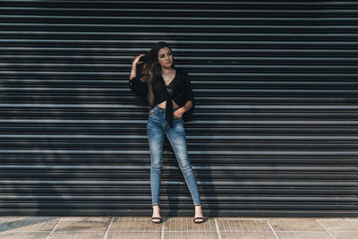 Portrait of a young woman standing against brick wall