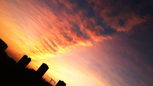 Low angle view of silhouette building against orange sky