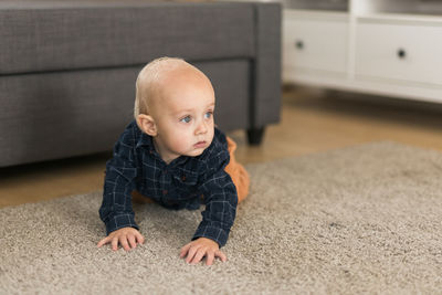 Portrait of cute baby boy lying on floor at home