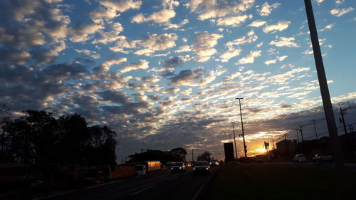 Cars on road against sky during sunset