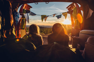 Rear view of woman lying in travel trailer during sunset