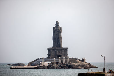 Scenic view of tall statue in sea against clear sky