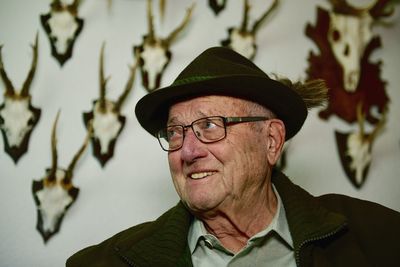 Close-up of man looking away against antlers on wall