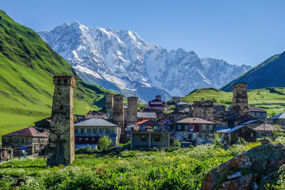 Scenic view of village and snowcapped mountains against clear sky