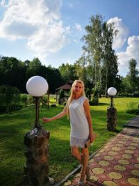 Portrait of beautiful young woman standing on footpath in public park