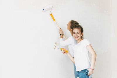 Beautiful and happy mom and daughter paint the walls in the apartment white.