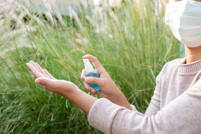 Midsection of person using mobile phone in field