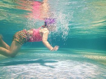 Girl swimming underwater in pool