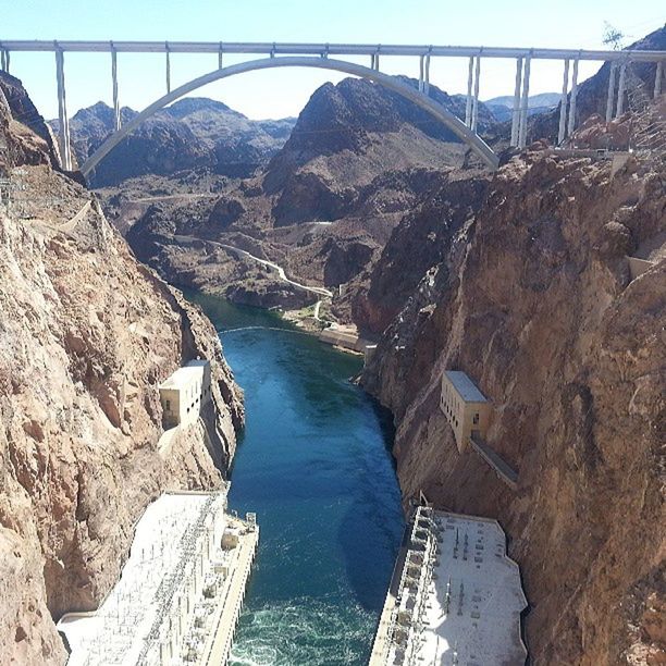 mountain, water, built structure, architecture, connection, sea, mountain range, high angle view, day, river, nature, bridge - man made structure, railing, famous place, sky, rock - object, tranquility, travel destinations, rock formation, scenics