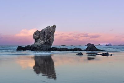 Rocks on shore against sky during sunset