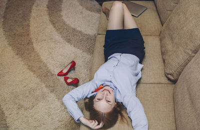 High angle view of smiling woman lying on couch at home