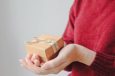 Midsection of woman holding gift box against white background
