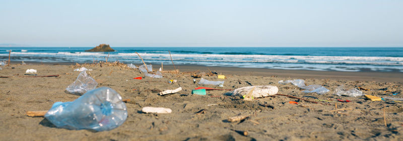 Garbage on sand at beach against sky