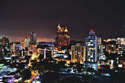 Illuminated buildings in city against sky at night