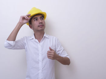 Young man looking away while standing against white background