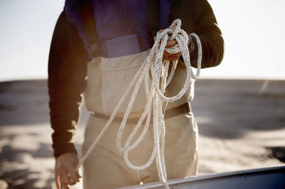 Midsection of man holding rope while standing at beach