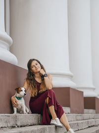 Full length of woman with dog sitting on steps outdoors