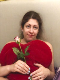 Portrait of young woman holding red flower