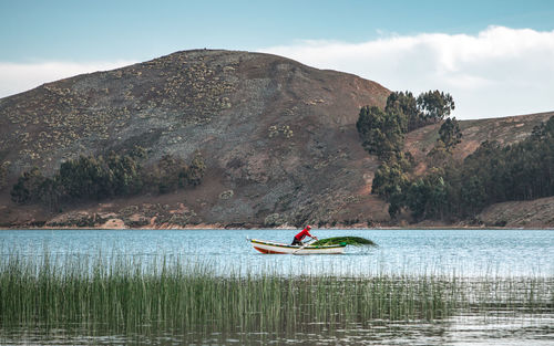 Man on boat in lake against sky