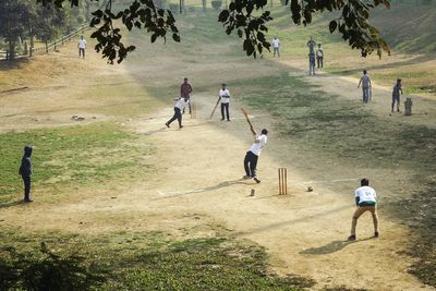Friends playing cricket on field