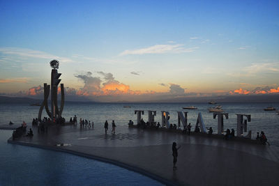 Silhouette people on beach against sky during sunset