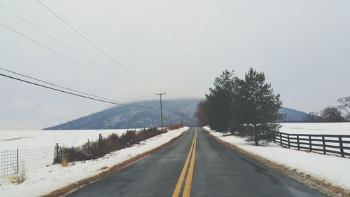 Empty road along snow covered landscape