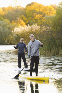 Two people smiling on paddle boards on river