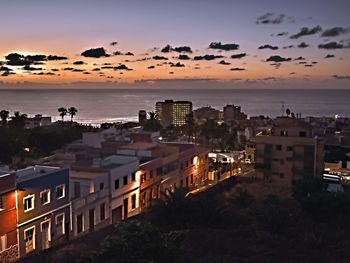 High angle view of buildings and sea against sky at sunset