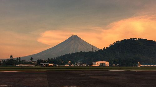 Scenic view of mountain and field against cloudy sky during sunset