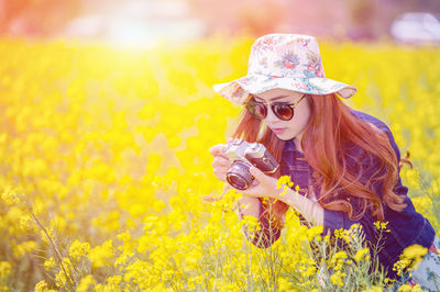 Woman photographing with camera at rape field