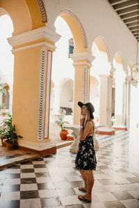 Side view of smiling young woman standing in hallway