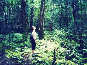 Full length of woman standing on tree trunk in forest