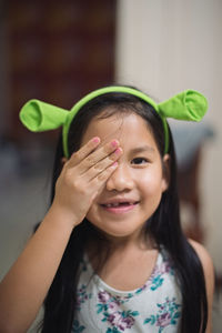 Portrait of smiling girl with hands covering eye
