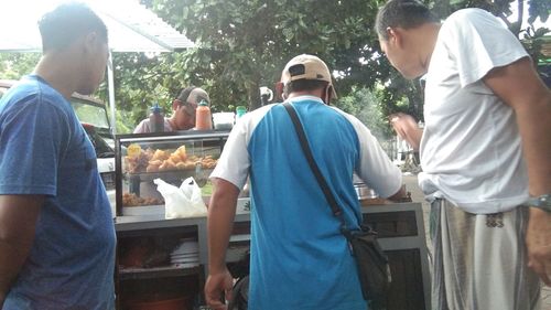 Rear view of people standing on barbecue grill