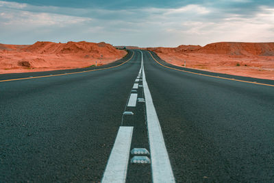 Empty road amidst landscape against sky