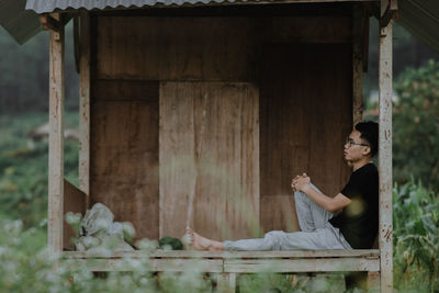 Full length of man sitting on wood