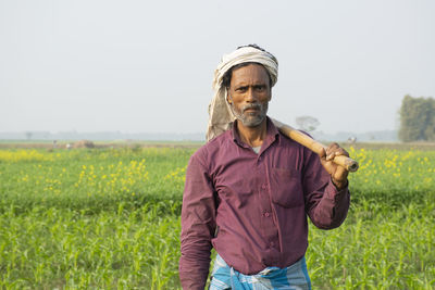 Portrait of indian farmer standing in field with spade