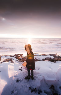 Side view of woman wearing warm clothing while standing on snow