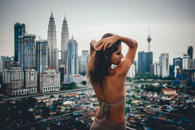 Woman standing by buildings against sky in city