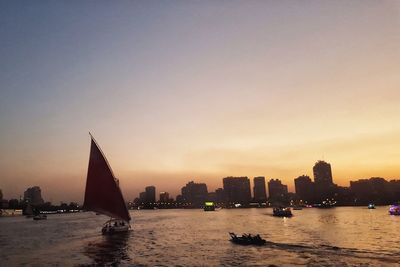 Silhouette boats sailing in sea against sky during sunset