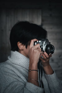 Portrait of woman photographing against wooden wall