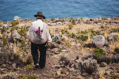 Rear view of man walking on dirt at beach