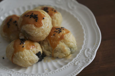 There are some delicious black sesame egg yolk pastries freshly baked on the plate on the table