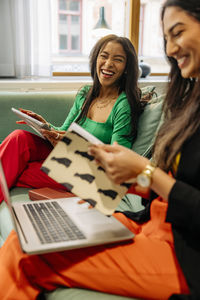 Happy businesswomen laughing while sitting together at office