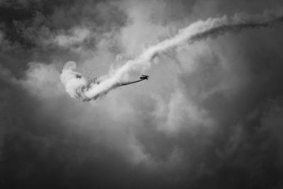 Low angle view of airplane flying against cloudy sky