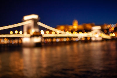 Illuminated bridge over river at night