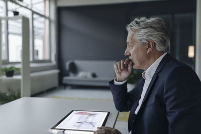 Senior businessman using tablet with architectural plan